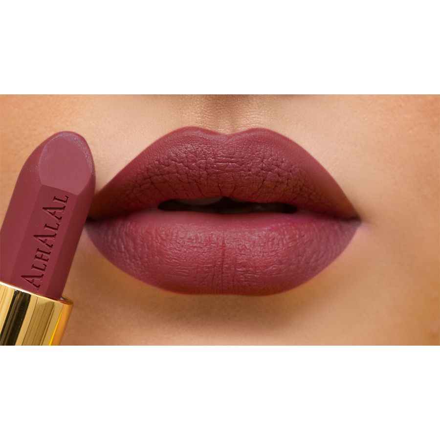 Rouge à lèvres velours Alhalal Cosmetics dans une teinte vin sur des lèvres féminines avec du texte ROUGE À LÈVRES AU VIN